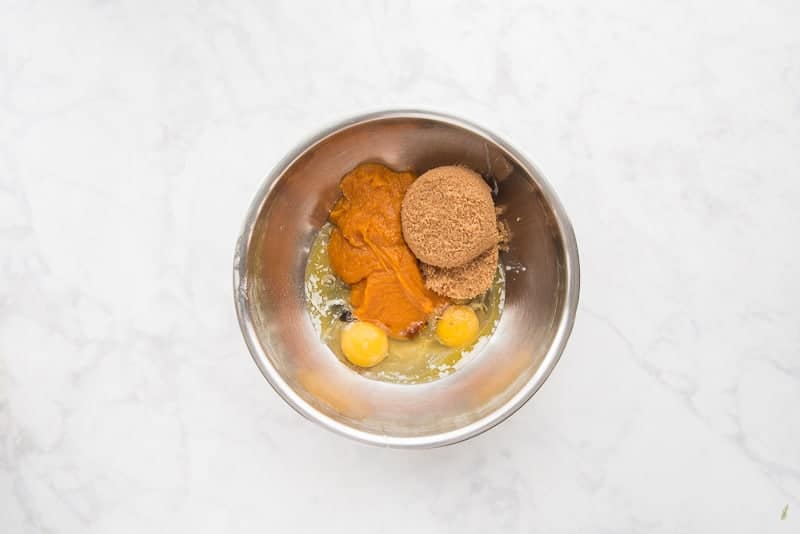 The sugar, eggs, pumpkin puree, butter, and vanilla are added to a small mixing bowl.