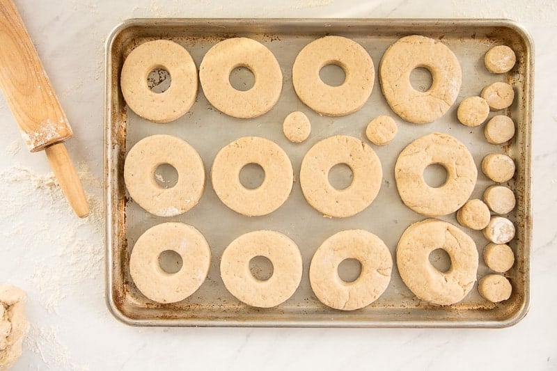 The Easy Cake Donuts are cut and arranged on a sheetpan before frying.