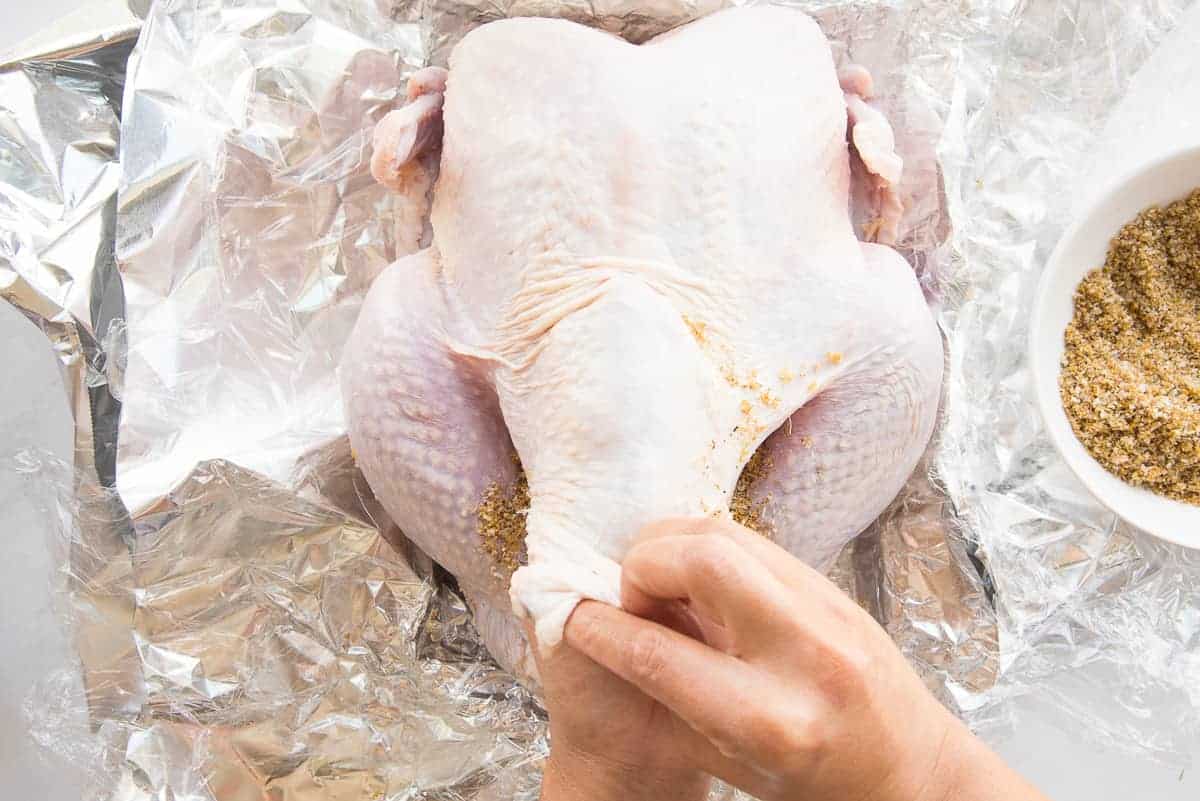 Rubbing the citrus herb dry brine under the skin of the turkey.