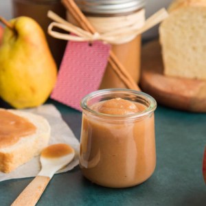 Preview for Slow Cooker Apple Pear Butter. Small glass jar of the fruit spread next to a slice of bread with the spread on it.