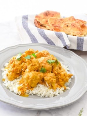 A serving of Vegetarian Curried Cauliflower on a bed of rice on a grey plate