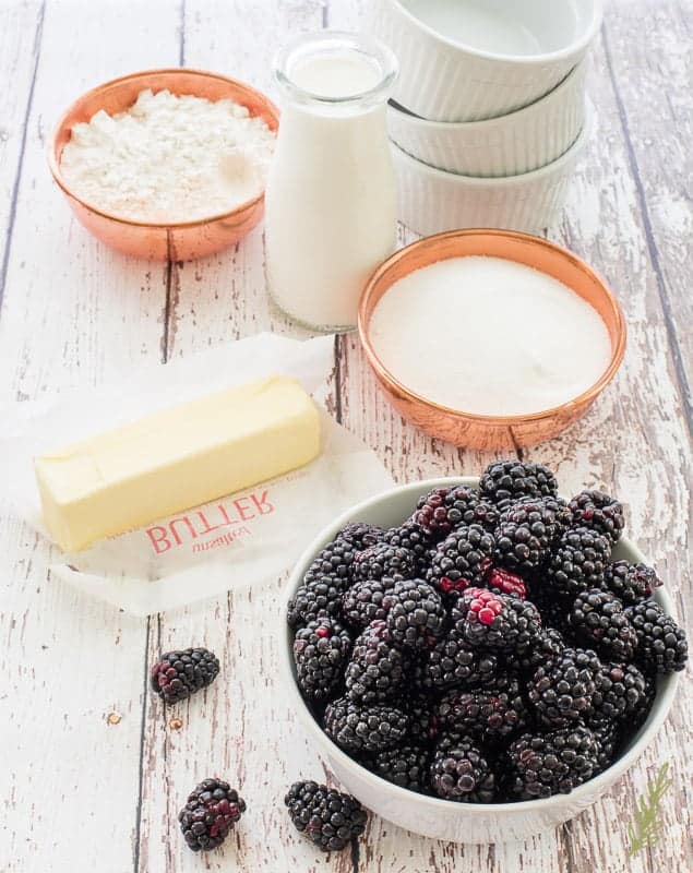 The ingredients needed to make Blackberry Cobblers: flour, butter, sugar, blackberries, milk, and ramekins to bake them in 