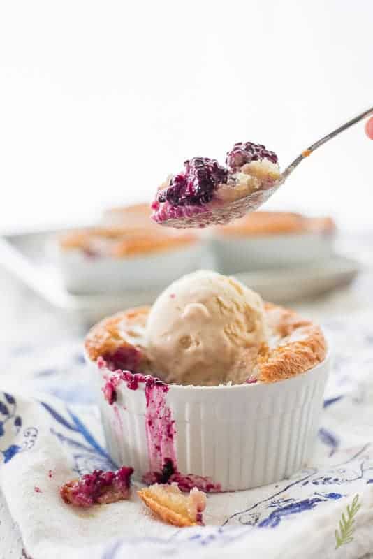 A spoon scoops a bit of the Blackberry Cobbler out of the individual ramekin. 