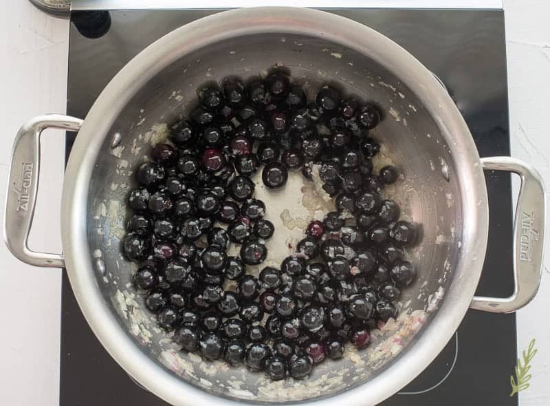 Blueberries are added to the pot with onions and garlic