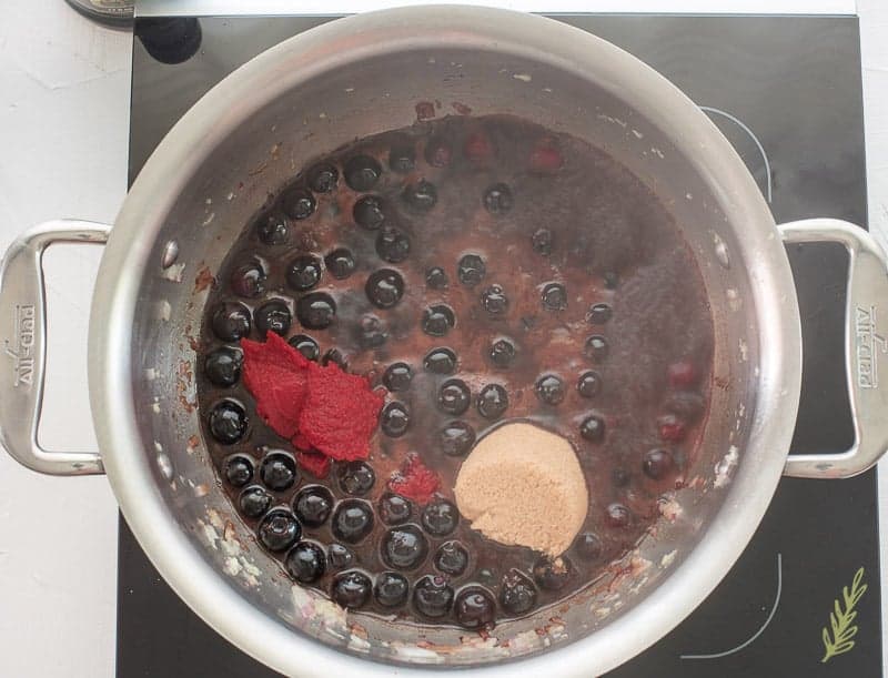 Tomato paste and brown sugar have been added to blueberry and vinegar mixture in the pot