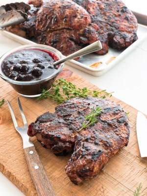 A Grilled Pork Chops with Blueberry Balsamic BBQ Sauce on a wooden cutting board