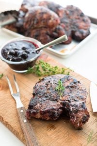 A Grilled Pork Chops with Blueberry Balsamic BBQ Sauce on a wooden cutting board
