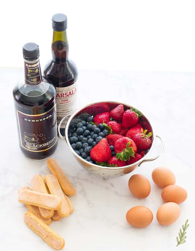 Basic ingredients needed to make Berry Tiramisu. Liqueurs, fresh berries, eggs, ladyfinger cookies 