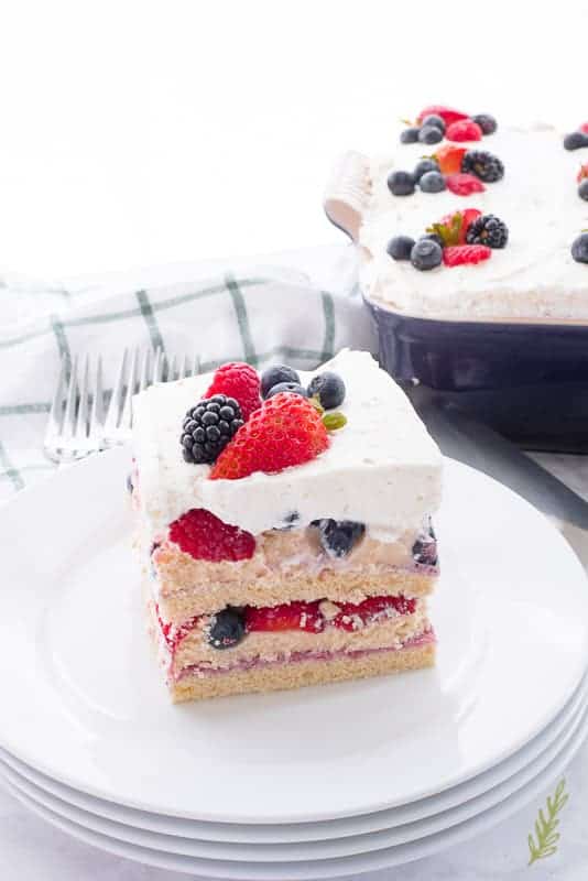 A serving of Berry Tiramisu is on the top plate of a stack of white plates. 
