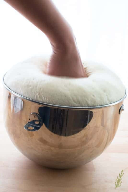 A hand punches down the pan sobao dough