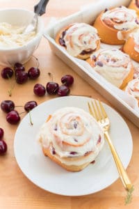 Cherry Sweet Roll with Cream Cheese Icing on a white plate with a gold fork