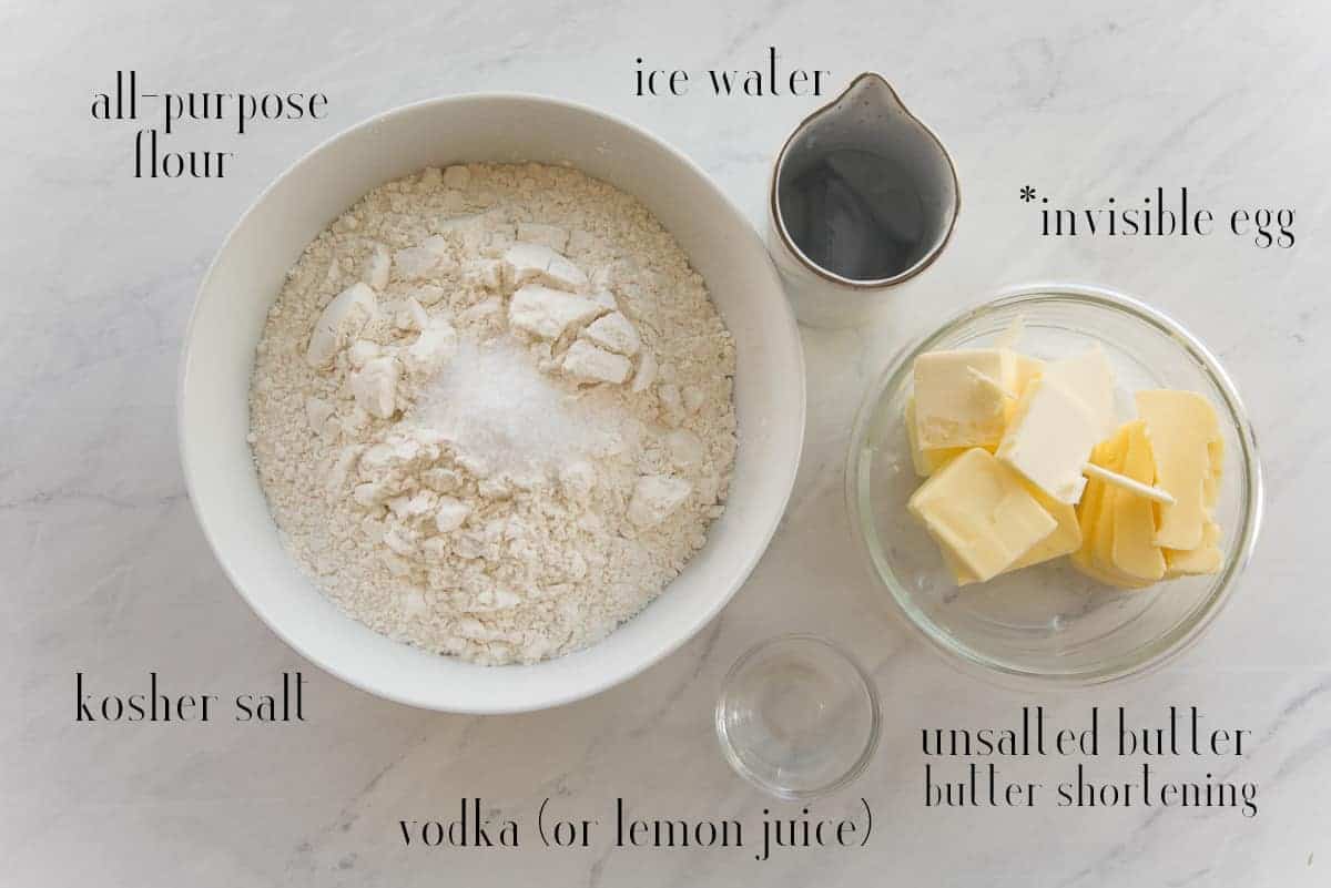 Ingredients needed to make Sense & Edibility's Mealy Pie Dough (Pate Brisee): all-purpose flour, ice water, egg (not pictured), unsalted butter, vodka (or lemon juice), kosher salt.