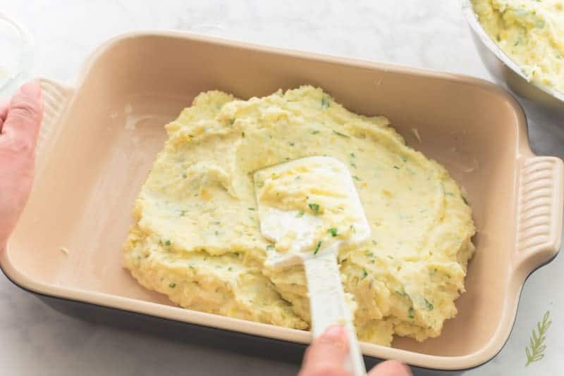 The Rustic & Rich Mashed Potatoes are smoothed into a lightly greased baking dish using a rubber spatula. 