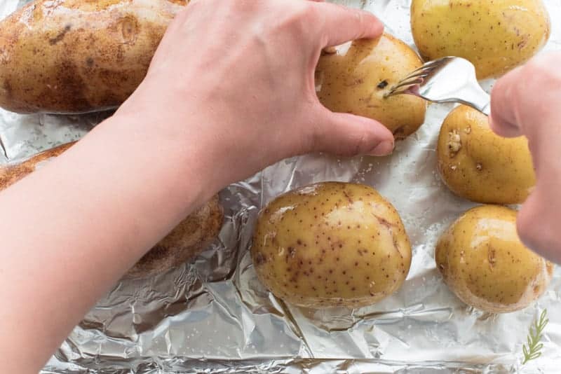 A fork is used to pierce holes in the oiled potatoes