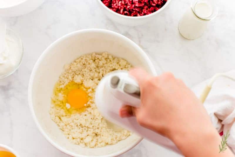 The eggs are added to the white mixing bowl of butter and sugar and blended in with a white mixer. 