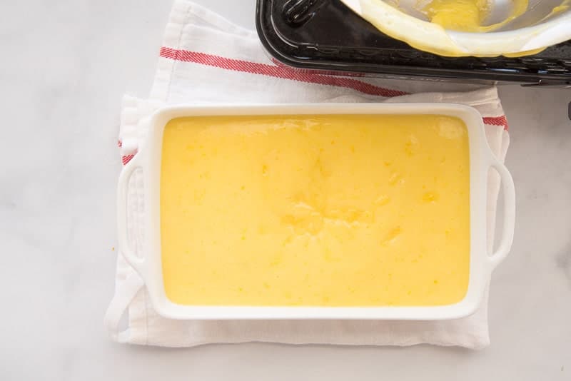 The thickened curd is poured into a rectangular white dish to cool.