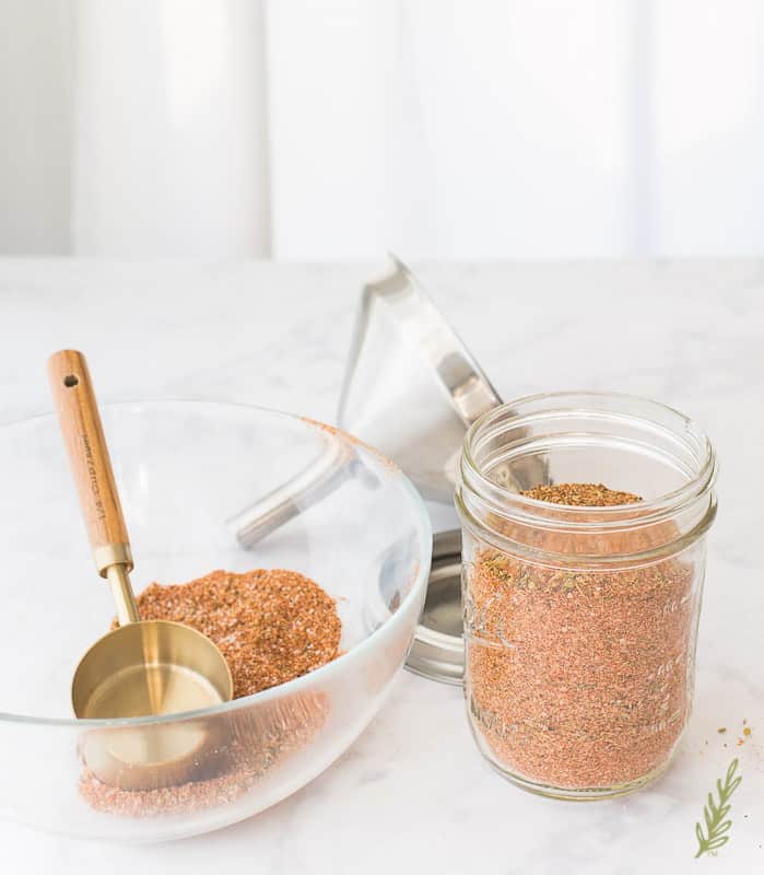 A mason jar filled with orange Meat Spice Blend next to a glass jar with more spice blend
