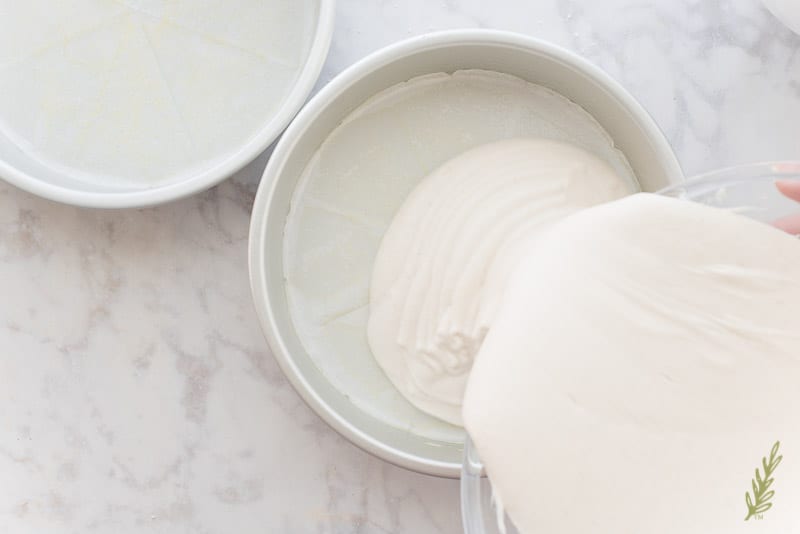 The Piña Colada Cake batter is poured into a silver cake pan which has been sprayed with non-stick baking spray and lined with a parchment paper square