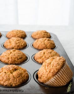 A panful of Oatmeal Carrot Cake Muffins with one skewed in its cup