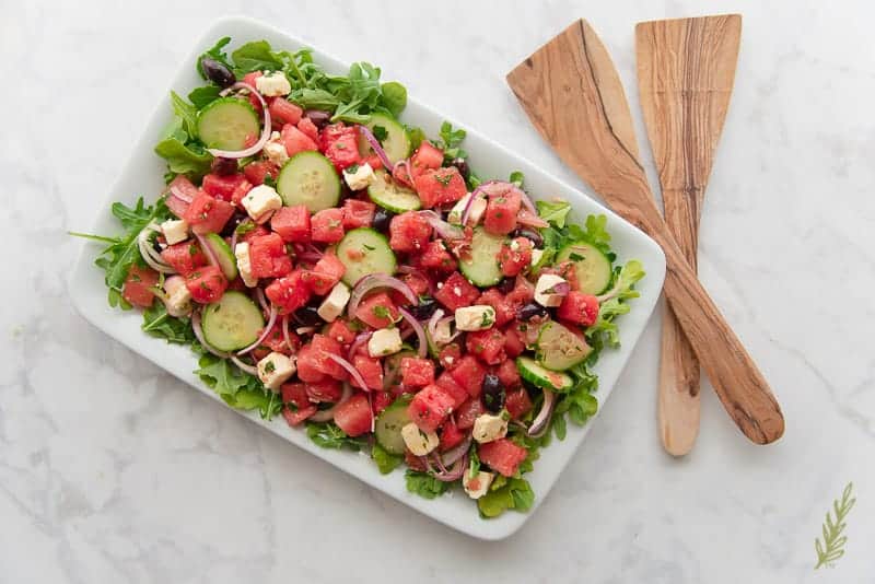 Overhead shot of the Greek Watermelon Farmer's salad platter with serving utensils
