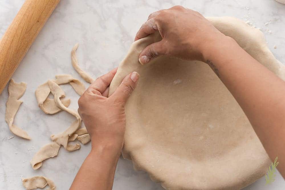 Folding over the pie dough to ensure a prettier crust