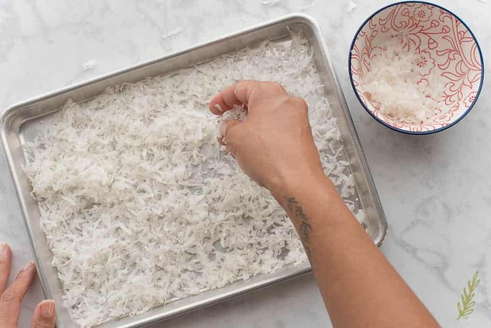 Spreading the coconut flakes in an even layer in the sheet pan