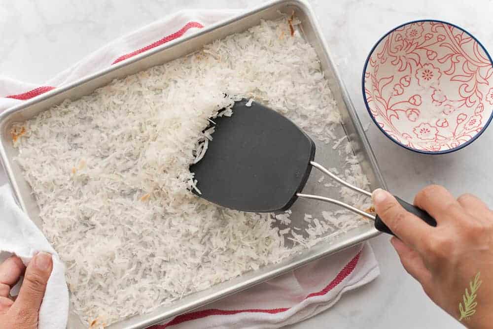 Stirring the toasted coconut flakes for even toasting