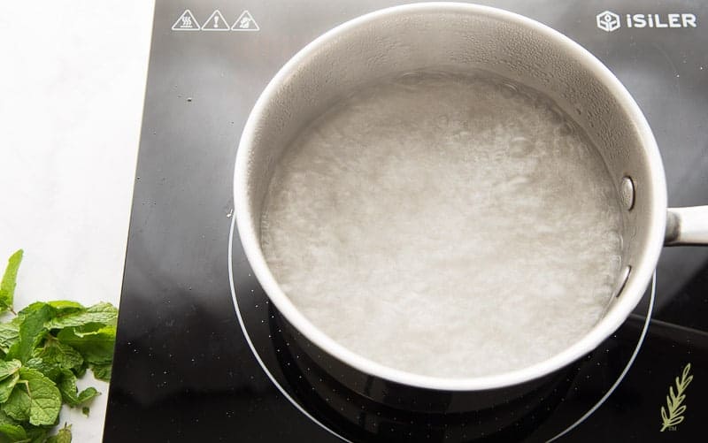 Boiling sugar and water together to create a simple syrup