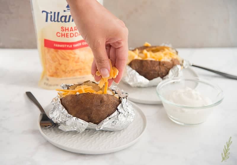 Sprinkling cheddar cheese on the slow cooker baked potato