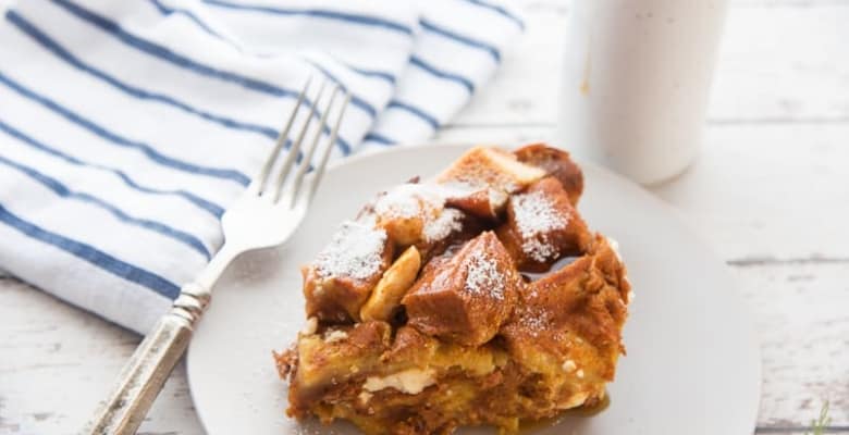 A plate of Pumpkin Cream Cheese Slow Cooker French Toast Casserole with a fork and the syrup jar next to it