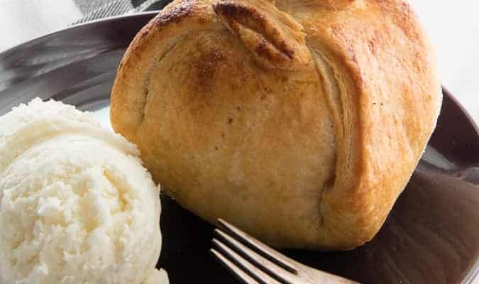 A baked Apple-Cranberry Dumpling with ice cream on a purple plate