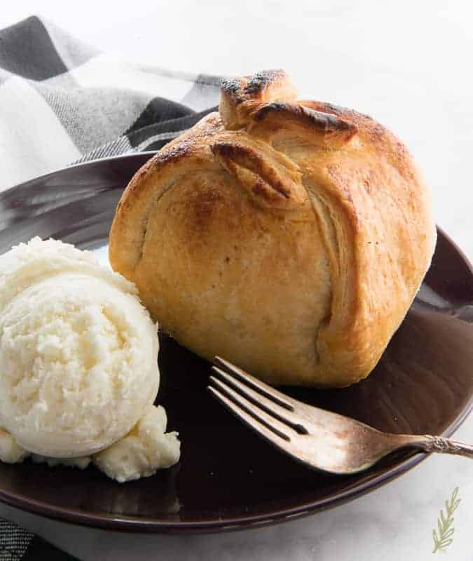 A baked Apple-Cranberry Dumpling with ice cream on a purple plate