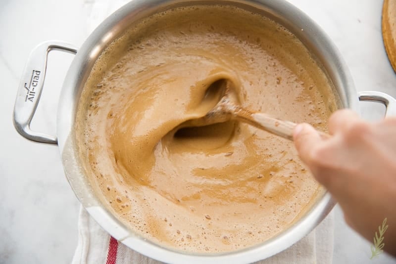 Quickly stirring the butter into the praline topping to cool it.