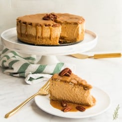 A slice of Sweet Potato Cheesecake with Pecan Praline Topping removed from the whole cheesecake which is in the background.