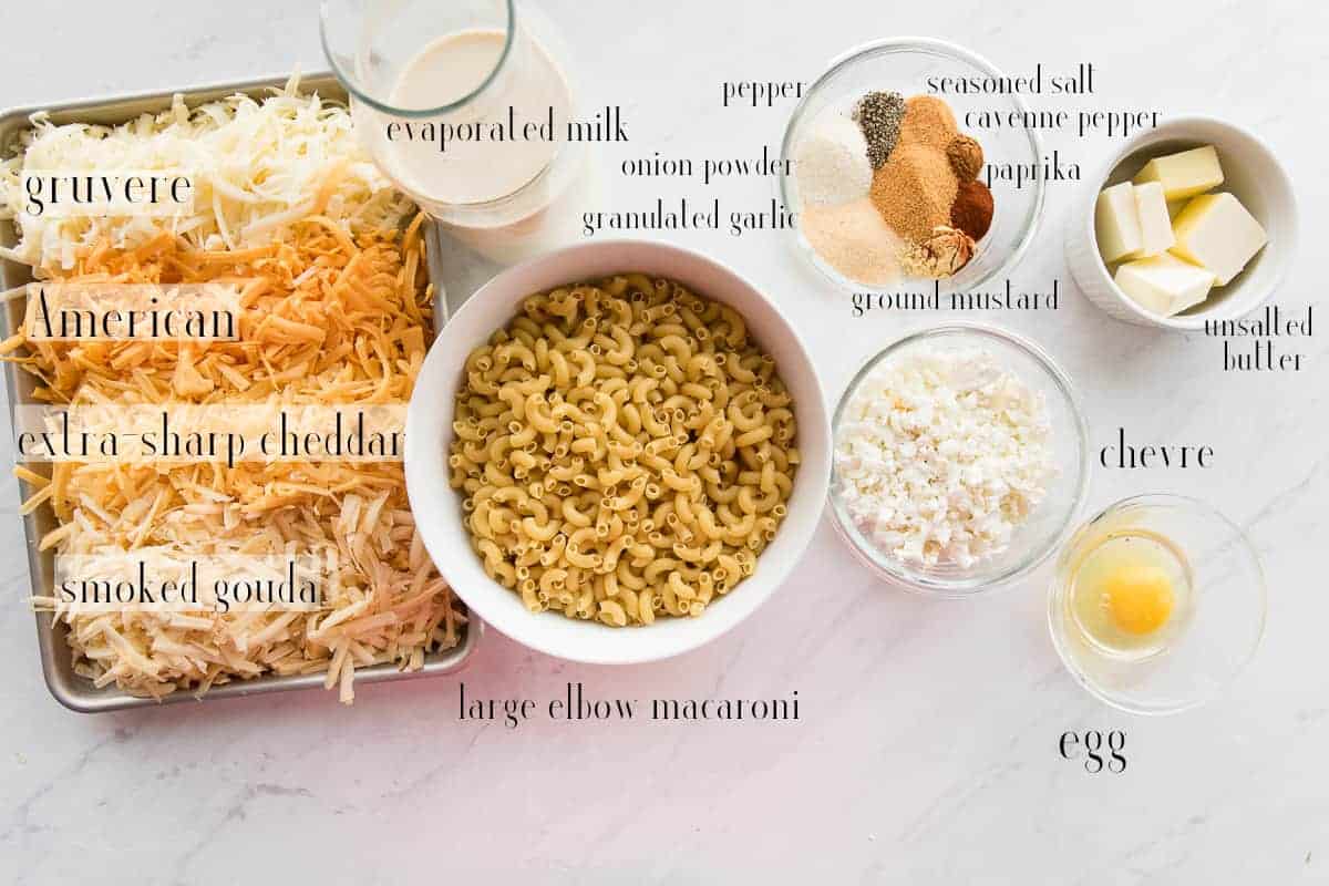 Ingredients to make Five Cheese Baked Macaroni and Cheese: shredded cheeses, evaporated milk, spices, butter, egg, chevre, and elbow macaroni.