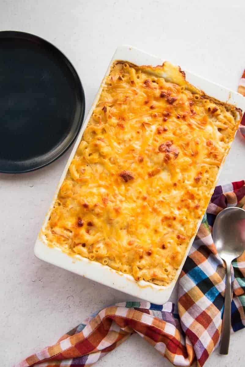 The Five Cheese Baked Macaroni and Cheese next to a colorful kitchen towel and a blue plate.