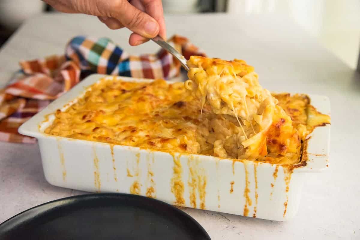 A spoonful of Five Cheese Baked Macaroni and Cheese is pulled from the baking dish.