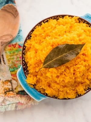 Overhead shot of the Arroz Borracho in a blue blue next to wooden spoons.