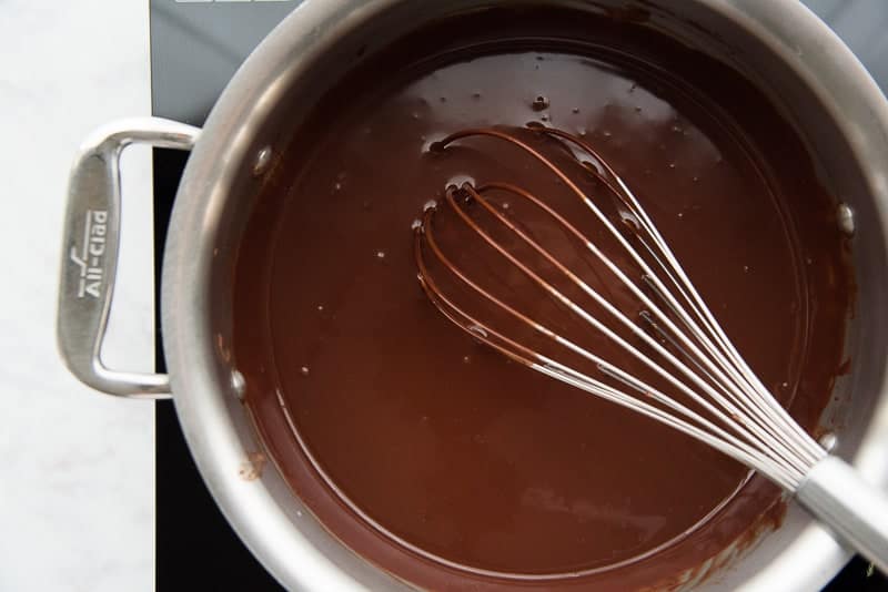 A whisk has just finished mixing the melted chocolate ganache