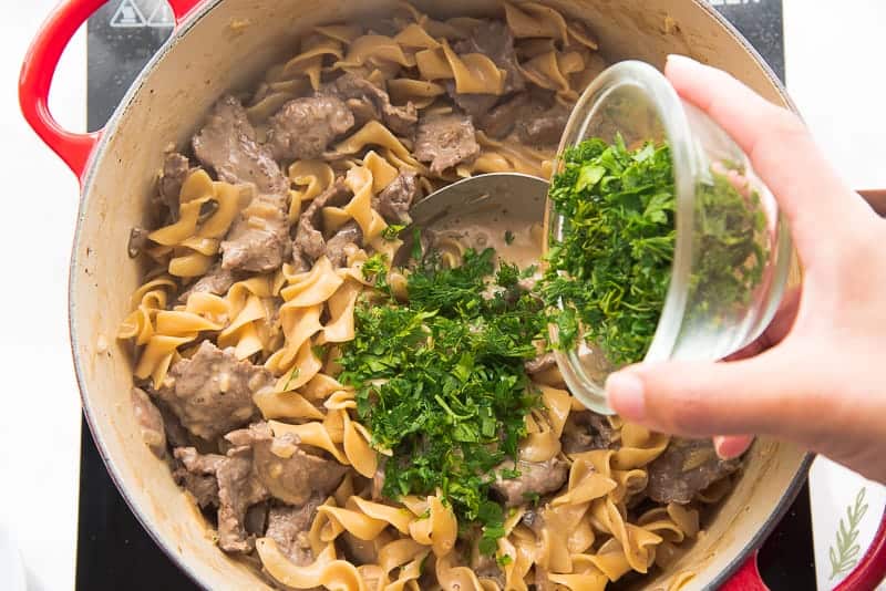 Adding the fresh herbs to the pot of beef stroganoff