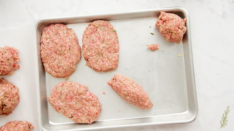 Balls of beef are formed into a football shape on a sheetpan