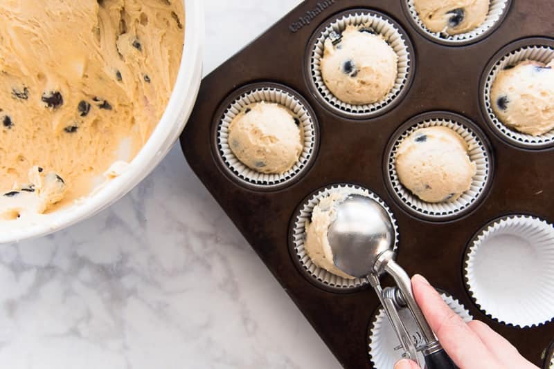 The muffin batter is scooped into the muffin tin.