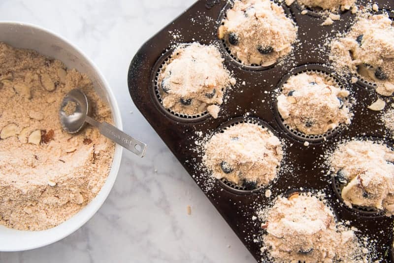 A generous amount of Almond Streusel is sprinkled over the muffin batter in the muffin tin. 
