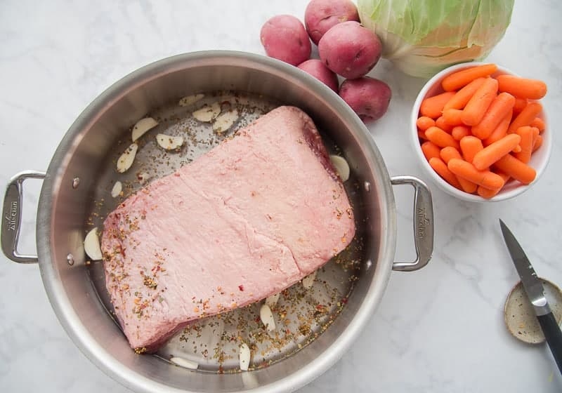 Slivers of garlic surround the corned beef in the pan