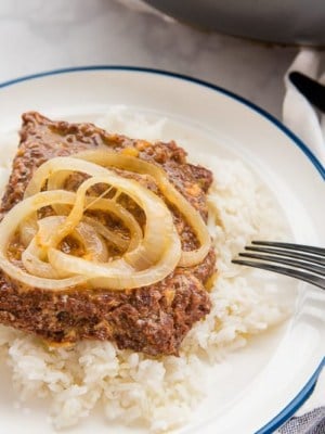 A side view of a plate with white rice and bistec encebollao