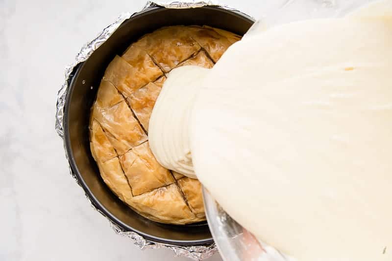 Pour the honey cheesecake batter onto the baked baklava crust