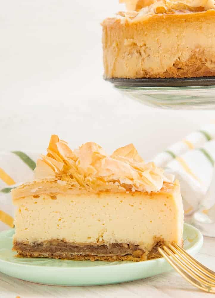 A sideview of a slice of Sense & Edibility's Honey Cheesecake with Baklava Crust sitting on a green plate