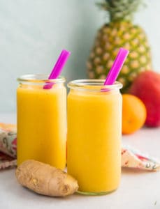Two glass jars filled with vitamin C smoothies with pink straws inside of them