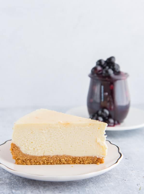 A single slice of Classic Cheesecake with Graham Cracker Crust on a white plate