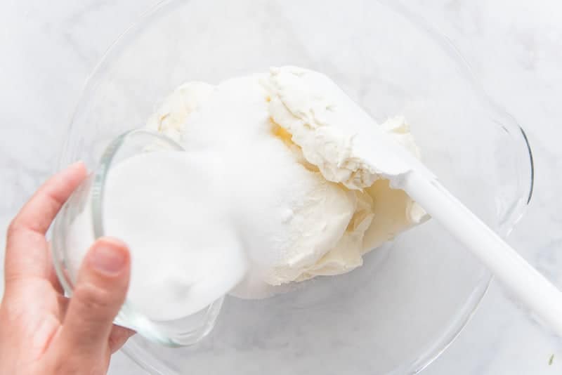 A glass bowl is filled with the cream cheese, sugar, and salt prior to being mixed until smooth